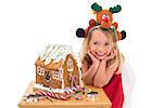 Festive little girl making gingerbread house on white background