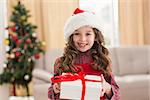 Festive little girl opening a gift at home in the living room