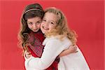 Festive little girls hugging and smiling on red background