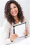 Beautiful young Latina Hispanic woman smiling, relaxing and using a tablet computer
