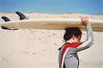 Surfer carrying surfboard on head at beach, Lacanau, France