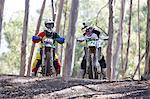 Two young male motocross riders chatting in forest