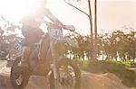 Cropped shot of young male motocross racer jumping mid air down mud hill