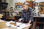 Young craftswoman checking components on workbench in pipe organ workshop