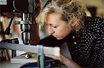 Young craftswoman drilling component in pipe organ workshop