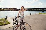 Portrait of young woman with bicycle on riverside, Danube Island, Vienna, Austria