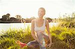 Young woman sitting on grassy riverbank, Danube Island, Vienna, Austria