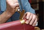 Close up of hands of senior male traditional bookbinder pressing gold leaf onto book spine