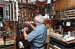 Senior man selecting tools in traditional bookbinding workshop