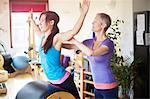 Female student leaning forward onto pilates barrel in pilates gym