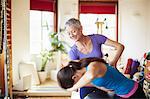 Young female student and tutor using pilates barrel in pilates gym