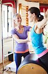 Young female student leaning forward onto pilates barrel in pilates gym