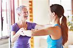 Young female student laughing with teacher in pilates gym