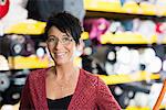 Portrait of mature seamstress in front of textile shelves in workshop