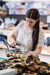 Young seamstress ironing tartan jacket in workshop