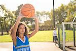 Young female basketball player holding up basketball