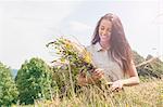 Young woman holding bunch of fresh picked wildflowers in field