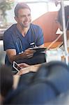 Doctor holding digital tablet, talking to patient undergoing medical treatment in outpatient clinic