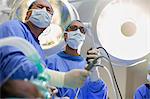 Low angle view of two surgeons holding laparoscopy equipment in operating theater