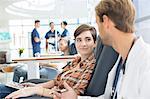 Doctor talking to patient undergoing medical treatment in outpatient clinic