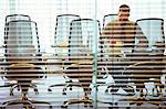 Businessman sitting behind blinds in conference room