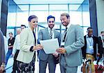 Portrait of businesswoman and two businessmen standing in lobby of conference center