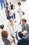 Businesswoman talking to conference participants, standing in lobby of conference center