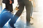 Cropped shot of two men walking side by side with trolley case