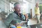 Older man using digital tablet at breakfast table