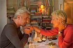 Older man kissing hand of wife at romantic dinner