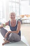 Older woman drinking juice on exercise mat