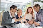 Business people using cell phone in office meeting