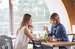 Businesswomen using cell phone in cafeteria