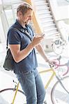 Man using cell phone and holding bicycle