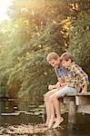 Father and son dangling feet in lake