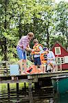 Father and grandfather fastening life jackets on boys