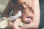 Mother holding and kissing baby wrapped in cloth after bath