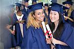 Portrait of smiling students with diplomas standing in corridor