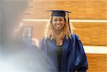 Female student in graduation gown posing for picture in university corridor