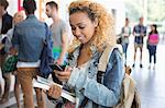 Female student standing in corridor and texting