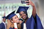 Two smiling female students taking selfie after graduation