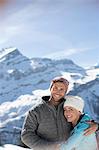 Portrait of smiling couple hugging below mountain