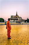Cambodia, Phnom Penh. Buddhist monk looking at silver pagoda, royal palace complex , at sunset (MR)