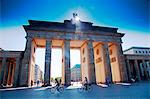 Germany, Berlin. Cyclists passing under the Brandenburg Gate