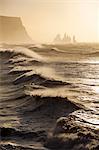 Iceland, Reynisfjara. Waves breaking on Reynisfjara beach, with the Reynisdrangar sea stacks on the horizon.