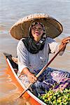 Indonesia, South Kalimatan, Lok Baintan. A woman in a wide-brimmed hat rows her small wooden boat at a floating market on the Barito River.
