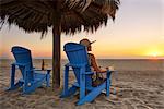 Woman sitting on beach at sunset, Rancho Pescadero, Baja California, Mexico MR