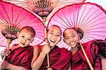 Myanmar, Mandalay division, Bagan. Portrait of three novice monks under red umbrellas (MR)