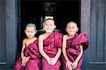 Myanmar, Mandalay division, Bagan. Three novice monks sitting outside a monastery (MR)