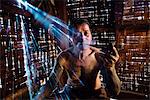 Myanmar, Shan state, Hsipaw. Burmese man with tattoos of shan ethnicity smoking pipe inside his house (MR)